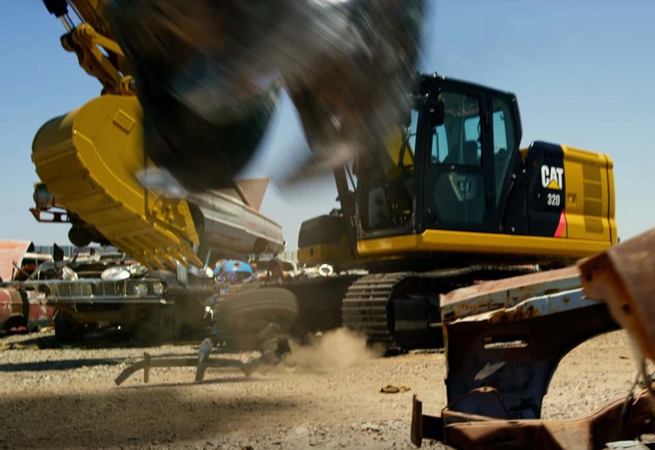 The foot of Grimlock, the Tyrannosaurus Rex-shaped leader of Dinobot, descends against the backdrop of a Caterpillar excavator. The foot of Grimlock, the Tyrannosaurus Rex-shaped leader of Dinobot, descends against the backdrop of a Caterpillar excavator.