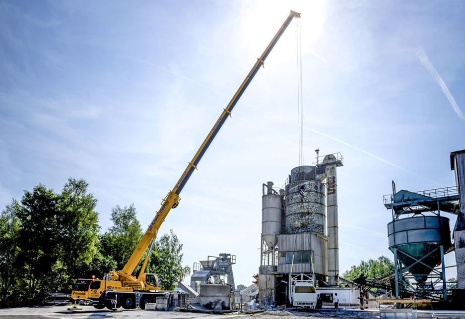 The mobile crane manoeuvres a feeder section for a Liebherr Betomix 2.5 mixing system, with the driver pictured standing to the right of the load. The mobile crane manoeuvres a feeder section for a Liebherr Betomix 2.5 mixing system, with the driver pictured standing to the right of the load.