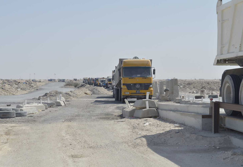 A line of trucks arrive at the site with construction waste to be recycled. A line of trucks arrive at the site with construction waste to be recycled.