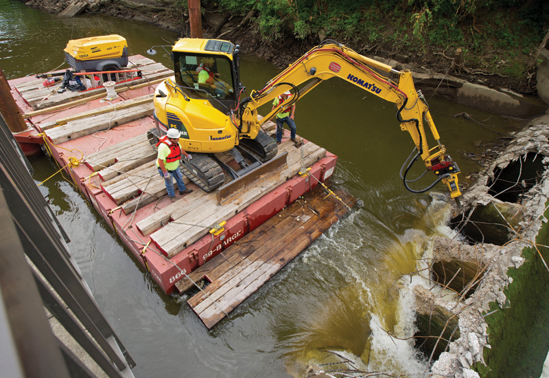 RiverReach used an Atlas Copco SB 552 breaker, a Komatsu mini excavator, and a modular barge to demolish the Sheraton Mill Dam. RiverReach used an Atlas Copco SB 552 breaker, a Komatsu mini excavator, and a modular barge to demolish the Sheraton Mill Dam.