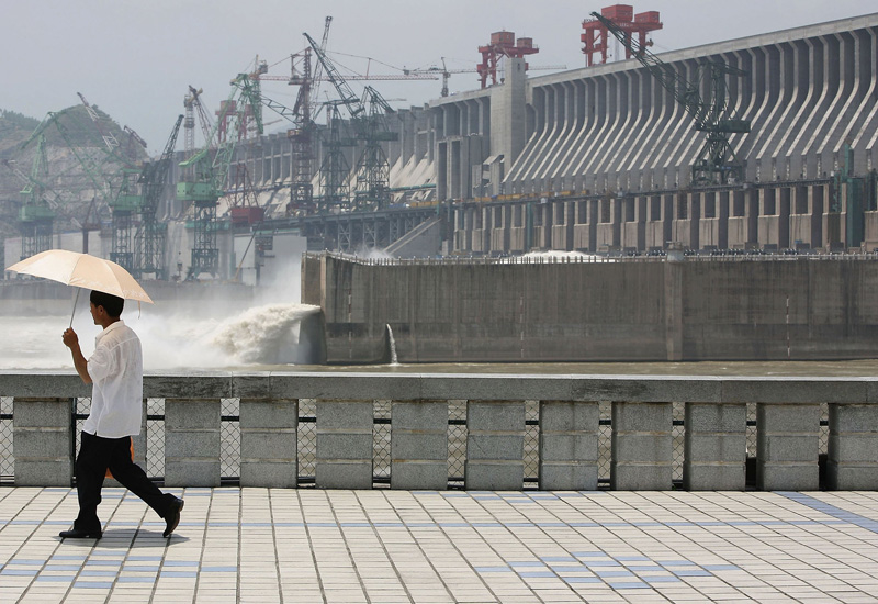 A tourist walks in front of the controversial Three Gorges Dam (Andrew Wong/Getty Images). A tourist walks in front of the controversial Three Gorges Dam (Andrew Wong/Getty Images).